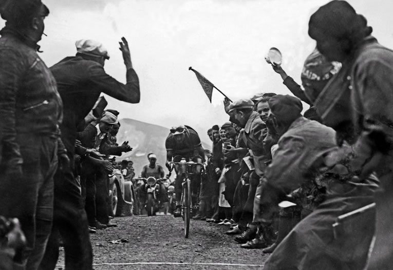 El piloto italiano Gino "el piadoso" Bartali encabezaba el Tour en 1937, en el momento en el que fue tomada la foto en el paso de Galibier. Posteriomente ganó el Tour de 1938. Pero es más conocido por haber ayudado a los partisanos en la Italia ocupada por los nazis, durante la II Guerra Mundial por ayudar a salvar la vida de 800 judios. Ganó el Tour de nuevo después de la guerra, en 1948, lo que le valió el récord de la mayor diferencia de tiempo entre victorias