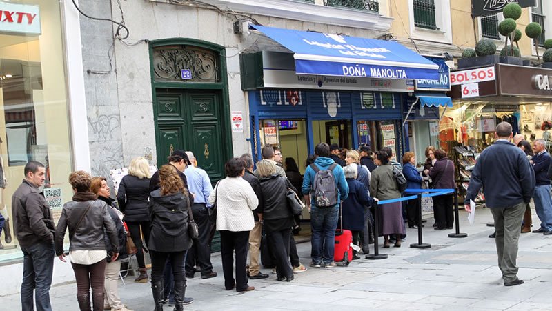 Personas intentando agenciarse un décimo en Doña Manolita, en la administración de la Puerta del Sol de Madrid